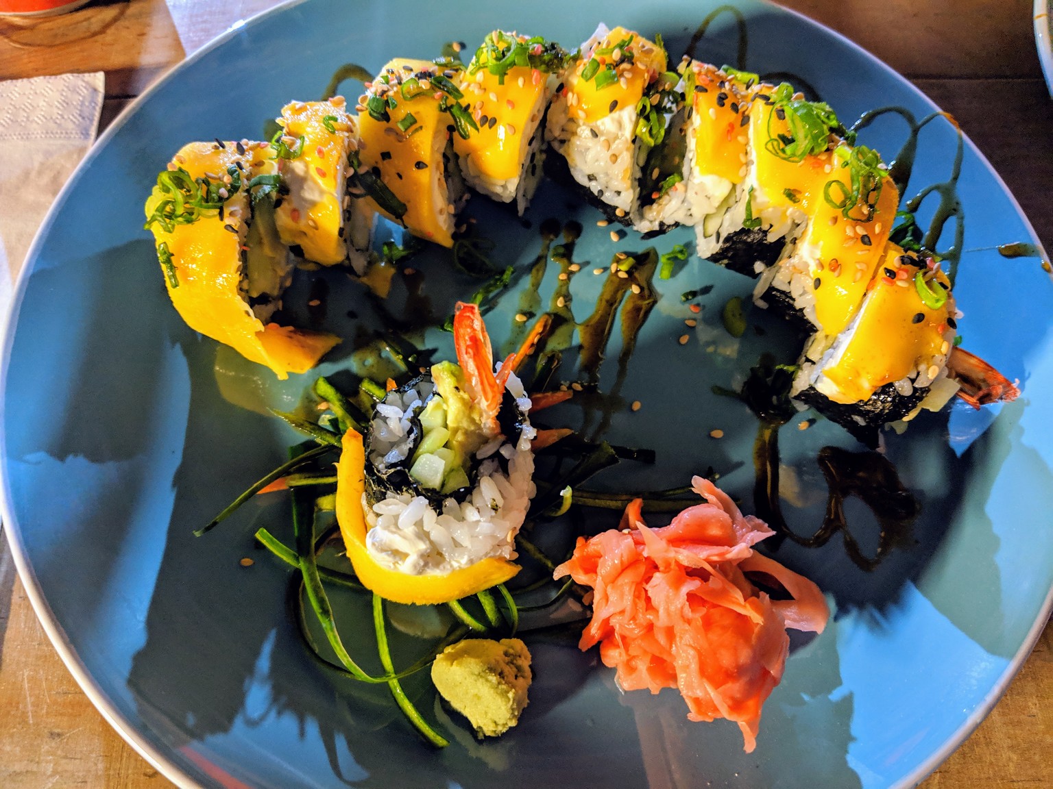 Sushi roll with shrimp inside and mango on top.