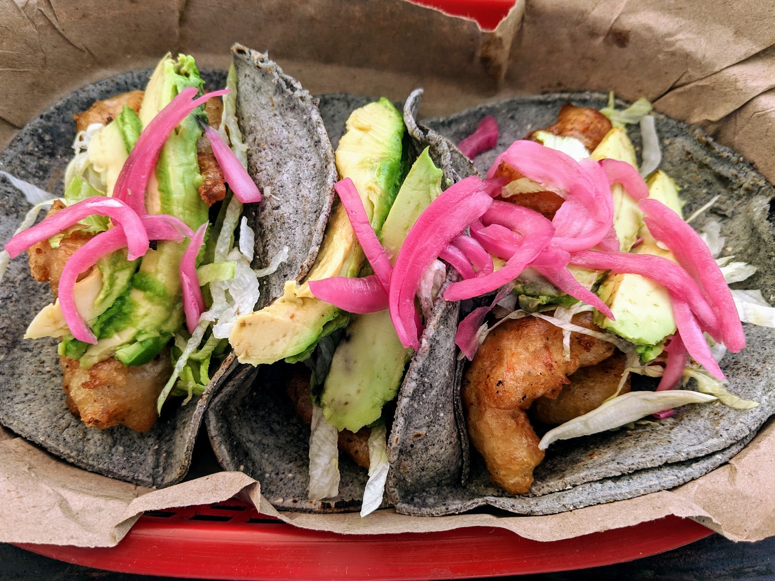 Fried shrimp tacos with pickled red onion and avocado on blue corn tortillas