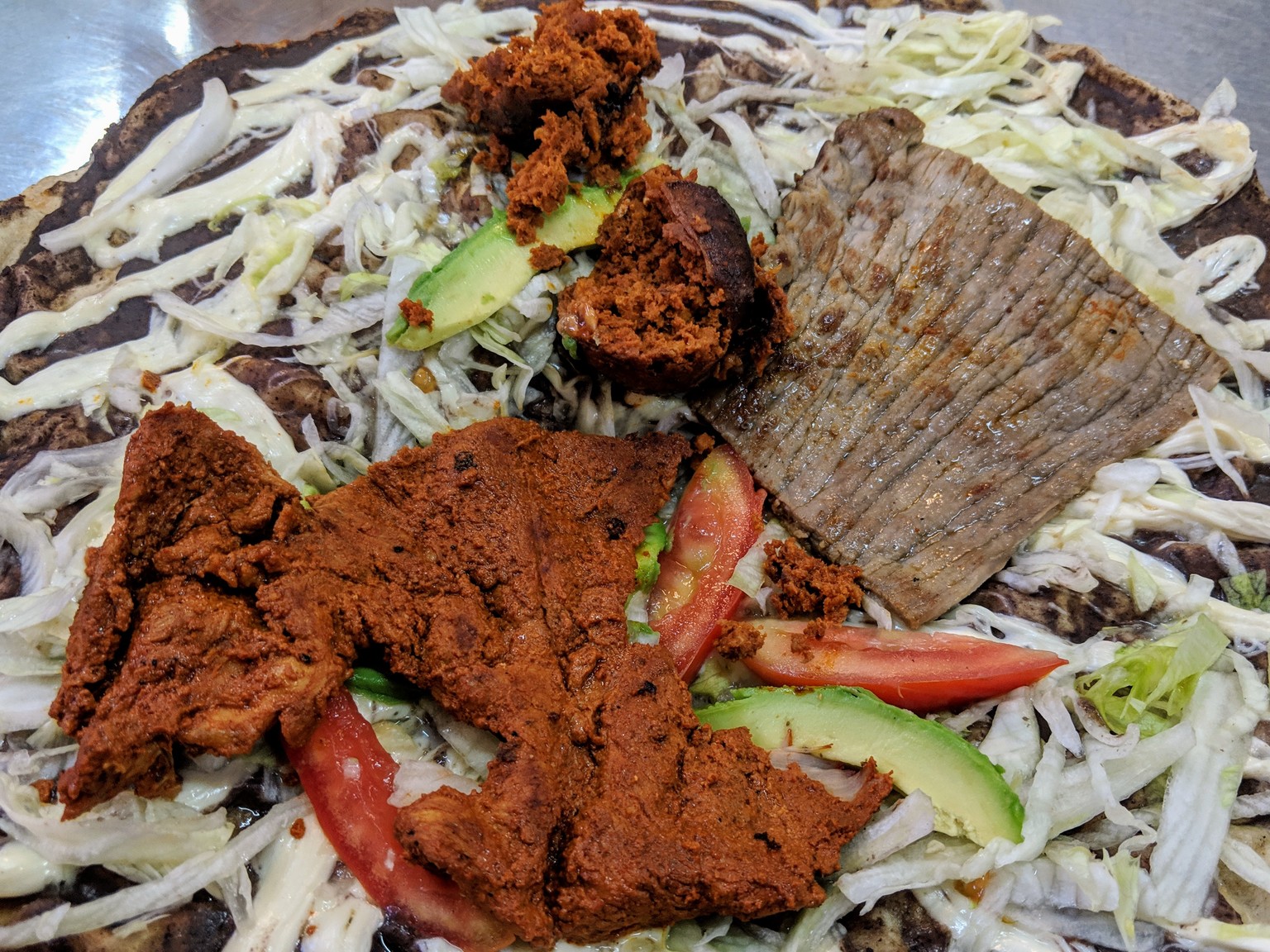 Tlayuda with chorize, marinated pork and carne asada.